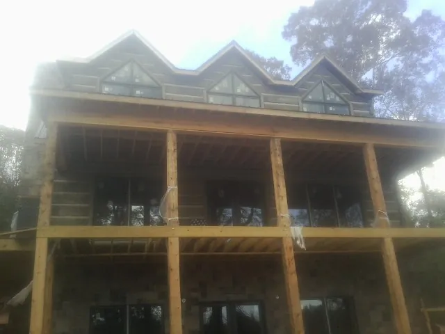 Dormers and porch framing on a large log home under construction — Roof Coating work by our crew in Pineville