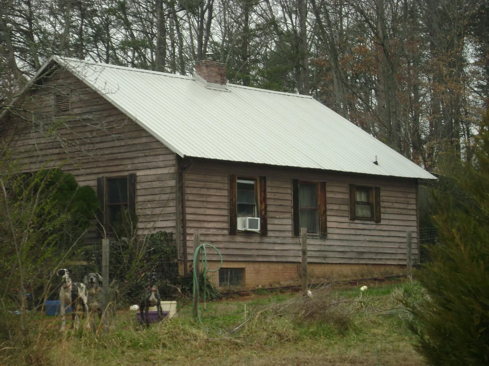 White metal roof on an old wood sided farmhouse, from a Metal Roof Installation job in Pineville