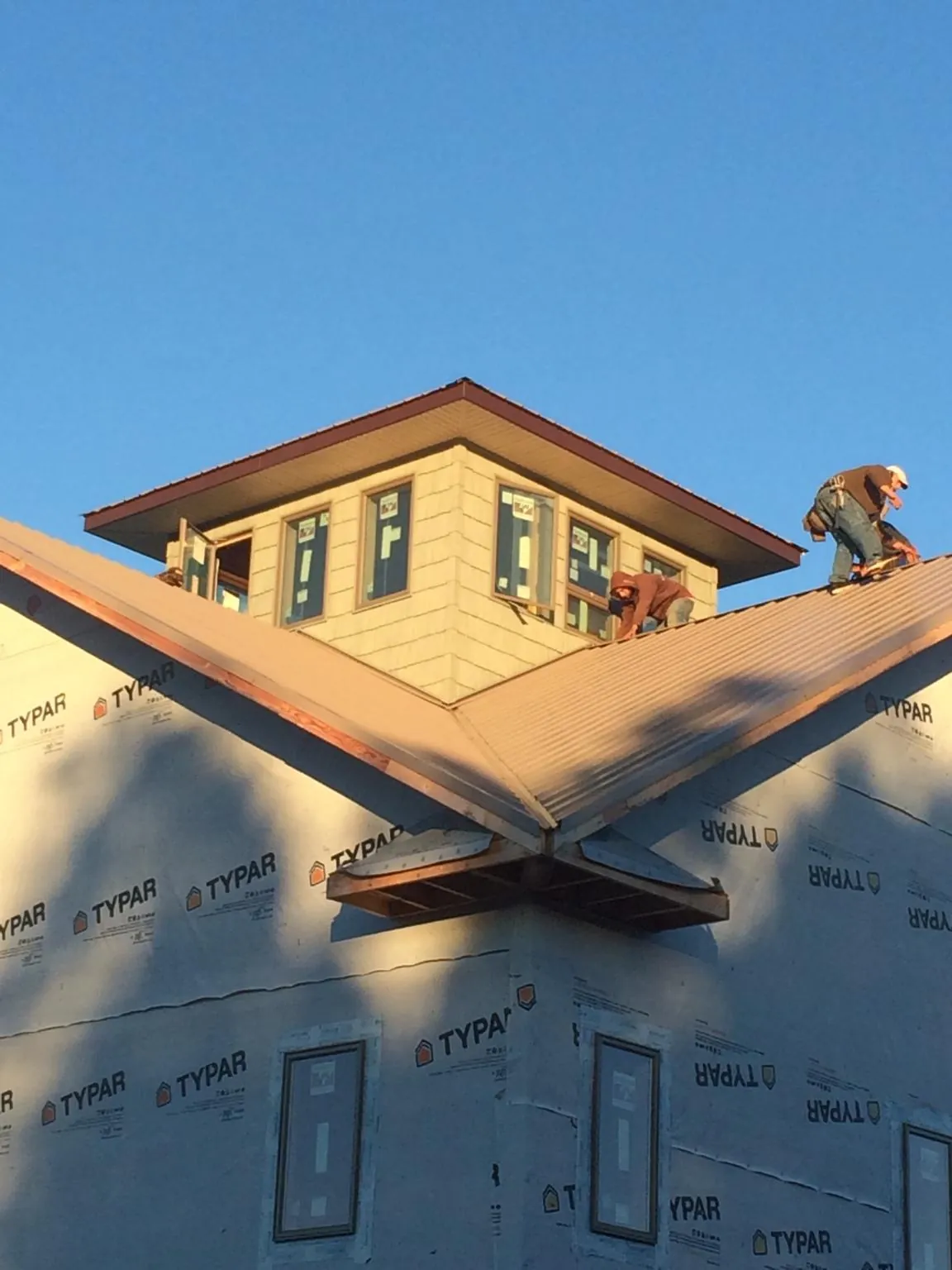 Roofers working around a rooftop cupola on a new metal roof at sunset — Roof Waterproofing in Pineville by Roofing Brothers